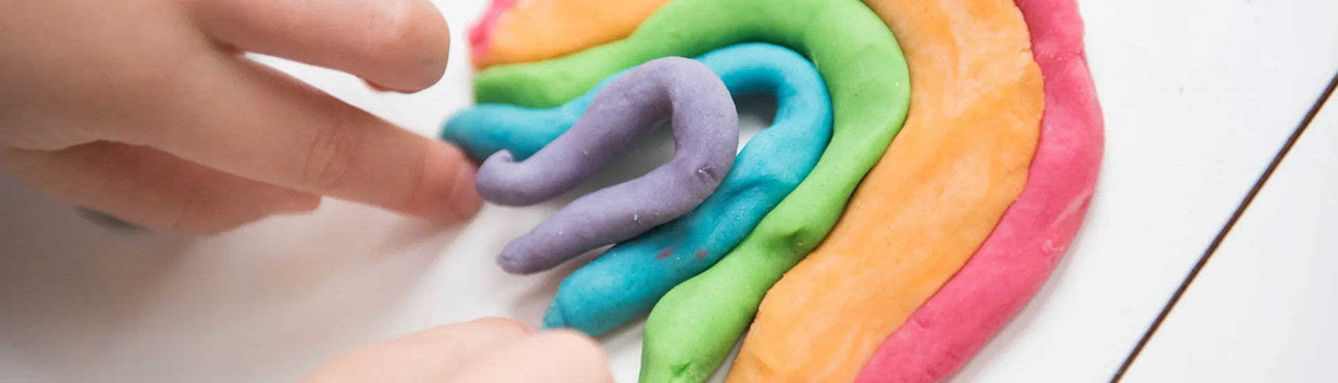 a person playing with colourful putty in a rainbow shape-fun fidgets