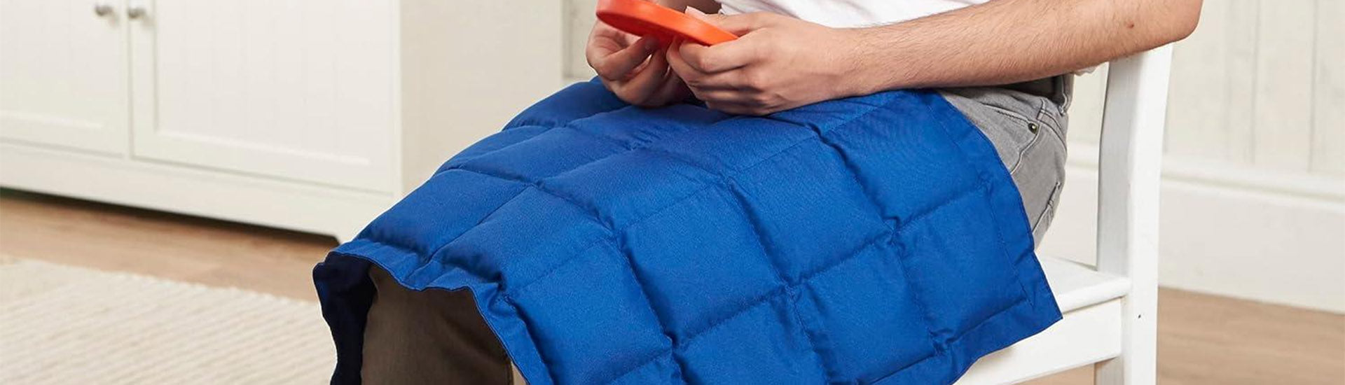 a person sitting on a chair with a blue weighted blanket across their lap-fun fidgets