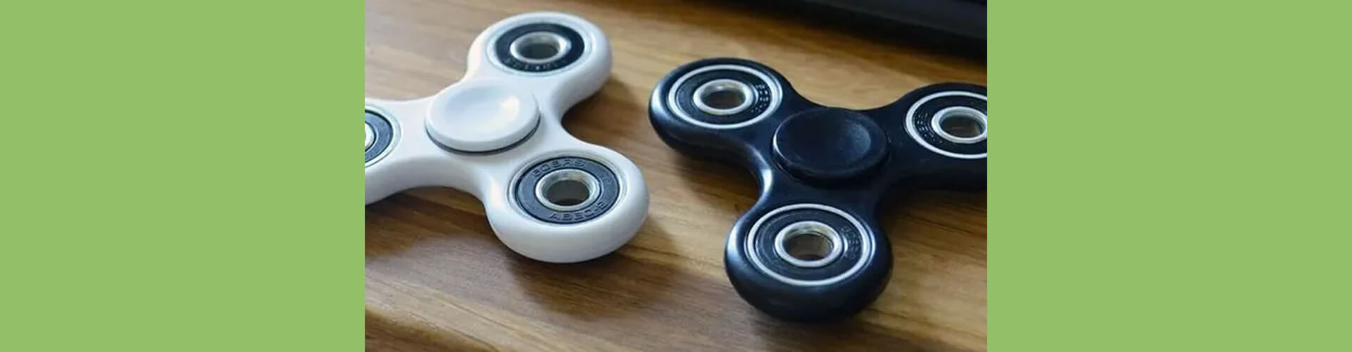 a black and a white fidget spinner on a wooden deck with a green background-fun fidgets