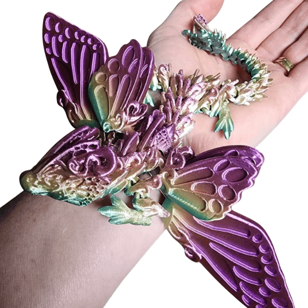 3D butterfly dragon with purple  wings laid out on a persons arm-fun fidgets