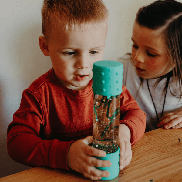 a young child looking a a teal calm down bottle-fun fidgets