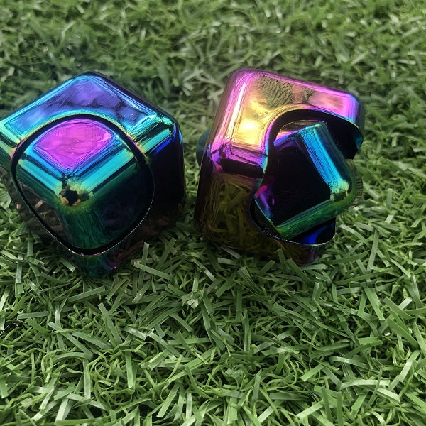 2 oil slick metal cubes resting on grass-fun fidgets