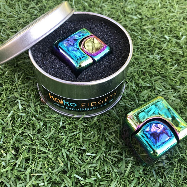 oil slick metal spinning cube shown in tin and on grass out of tin-fun fidgets